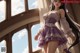 A woman in a purple dress standing in front of a window.