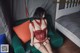A woman in a red lingerie sitting on a green chair.