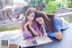 A couple of young women sitting at a table next to a pool.